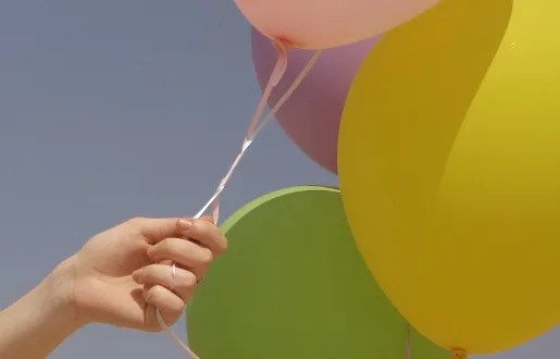 photo of hand holding balloons